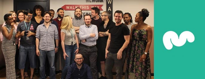 Group photo of Moonfruit employees next to the logo Group photo of Moonfruit employees next to the logo