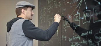Image of Nathan Moore sketching out plans on a chalkboard