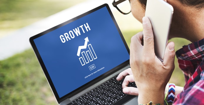 Photo of a man on the phone looking at a computer with a chart depicting growth on its screen Photo of a man on the phone looking at a computer with a chart depicting growth on its screen