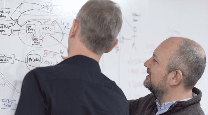 Photo of IT pros looking at a whiteboard with systems architecture blueprints Photo of IT pros looking at a whiteboard with systems architecture blueprints