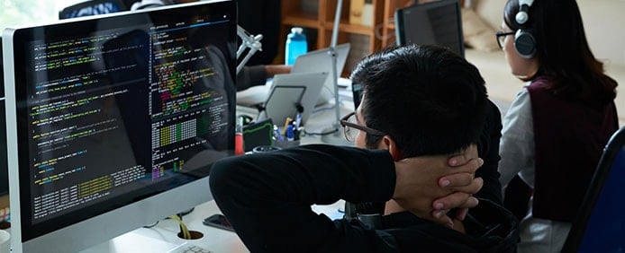 Image of developers sitting in front of code Image of developers sitting in front of code