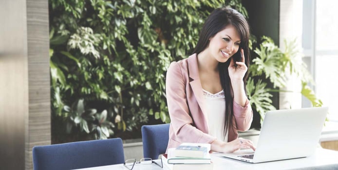 Image of woman on the phone next to a laptop Image of woman on the phone next to a laptop