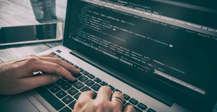 Image of hands typing code on a laptop Image of hands typing code on a laptop
