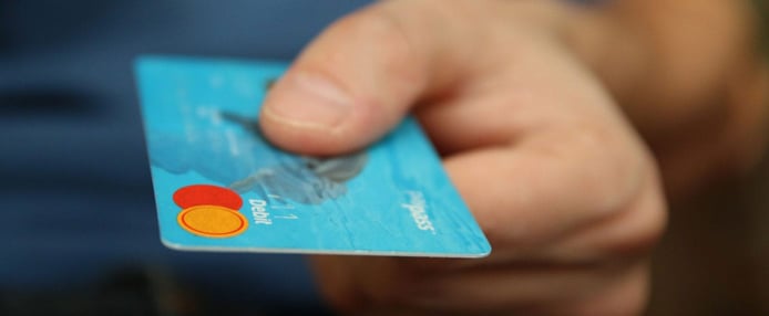 Image of a hand extending to pay with a credit card Image of a hand extending to pay with a credit card