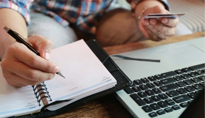 Image of someone making an online payment next to a notebook