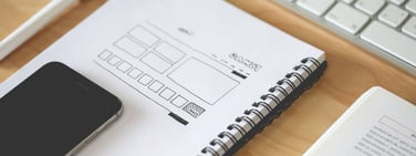 Image of wireframe website design next to a phone