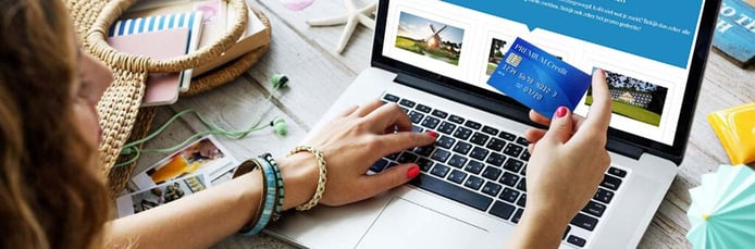 Image of woman holding a credit card near a laptop Image of woman holding a credit card near a laptop