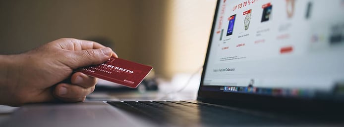 Image of hand holding a credit card near a laptop Image of hand holding a credit card near a laptop