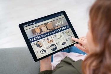 Back view of woman doing shopping online on website with digital tablet at home. Top view of lady on relaxing sofa. Rear view of girl hand touching screen while selecting product on e-commerce portal.