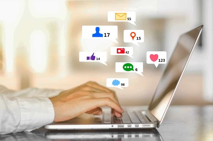 Hands on laptop keyboard with creative social media icons floating above Hands on laptop keyboard with creative social media icons floating above