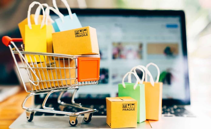 Shopping cart and packages next to laptop Shopping cart and packages next to laptop