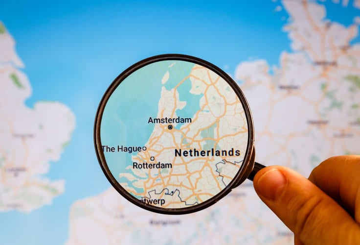 A map of Europe with a magnifying glass zeroing in on the Netherlands. A map of Europe with a magnifying glass zeroing in on the Netherlands.