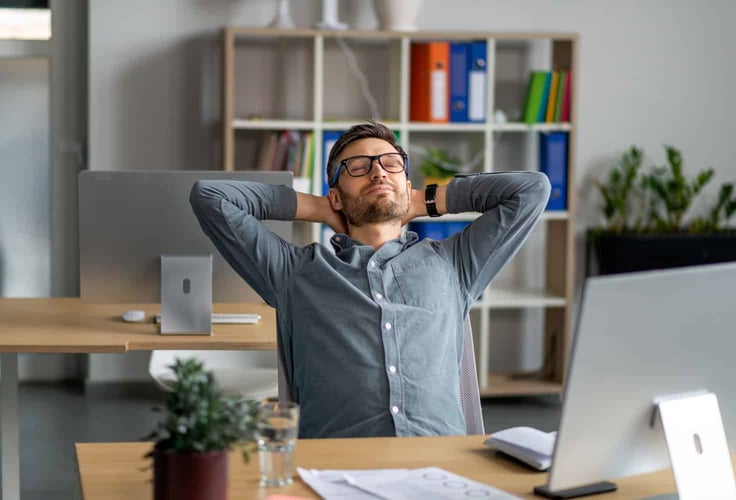 A man sitting at his work computer, happily relaxing. A man sitting at his work computer, happily relaxing.