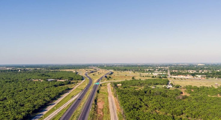 Aerial establishing shot of Abilene Texas with traffic flowing on highway 20 and a blue sky.