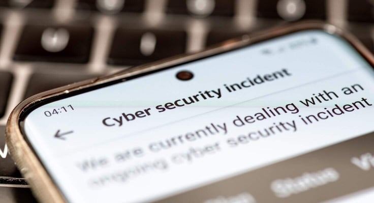 Close up of a message on a mobile phone from a company informing its clients of an ongoing cyber security incident.