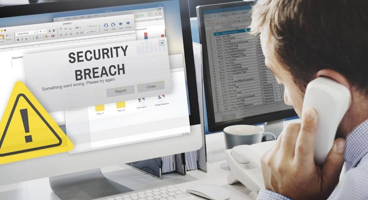 Man on the telephone in front of a computer screen that reads 'security breach'