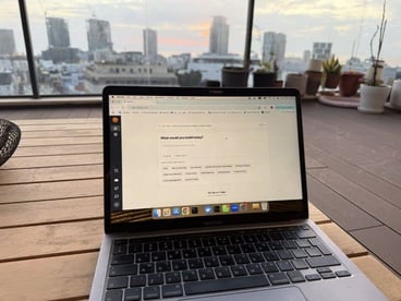 A photo of a laptop on a table with a city skyline in the background