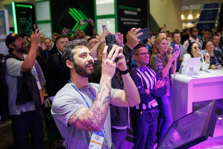 Attendees crowding the expo floor at RSA 2026, many holding up phones to photograph a demonstration Attendees crowding the expo floor at RSA 2026, many holding up phones to photograph a demonstration