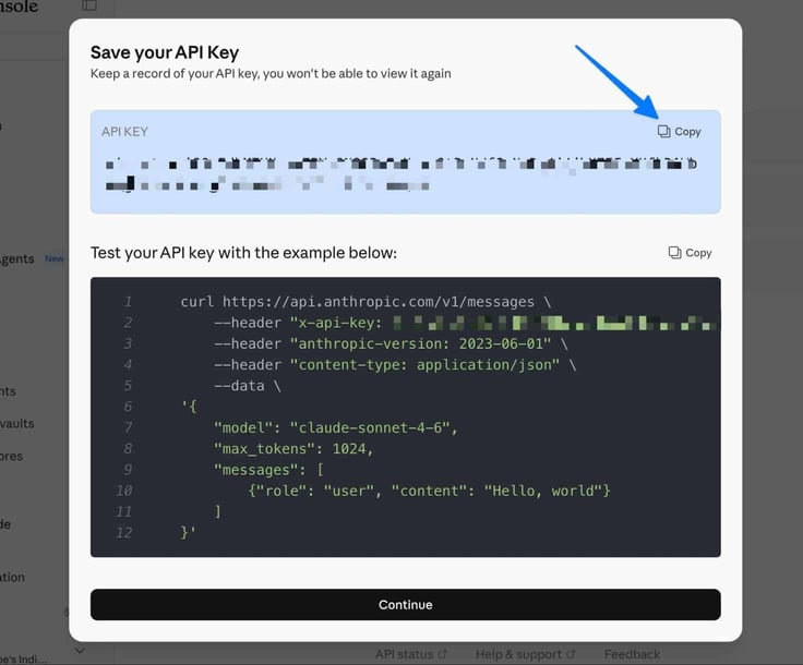 Anthropic Console Save your API Key modal dialog showing a partially redacted API key in a blue highlighted box with a Copy button pointed to by a blue arrow, and a dark-themed curl command example below showing how to test the key against the claude-sonnet-4-6 model with a Continue button at the bottom Anthropic Console Save your API Key modal dialog showing a partially redacted API key in a blue highlighted box with a Copy button pointed to by a blue arrow, and a dark-themed curl command example below showing how to test the key against the claude-sonnet-4-6 model with a Continue button at the bottom