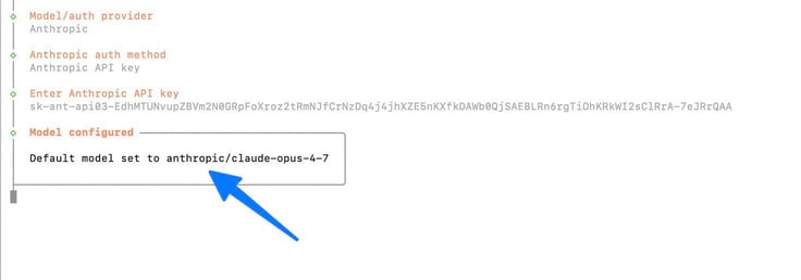 OpenClaw configure terminal showing the Model configured success confirmation with the Anthropic provider set, API key entered starting with sk-ant-api03, and a blue arrow pointing to the boxed confirmation message "Default model set to anthropic/claude-opus-4-7"