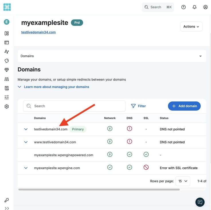 WP Engine hosting control panel Domains management page for myexamplesite showing four domains listed including primary domain testlivedomain34.com with DNS not pointed status, and a red arrow highlighting the primary domain label