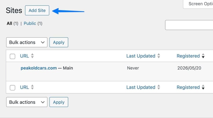 The WordPress Network Admin Sites page, prior to adding subdomains, shows only one registered site total with a blue arrow pointing to the "Add Site" button next to the "Sites" heading, and the single listed entry for peakoldcars.com marked as the Main site and registered on 2026/05/20. The WordPress Network Admin Sites page, prior to adding subdomains, shows only one registered site total with a blue arrow pointing to the "Add Site" button next to the "Sites" heading, and the single listed entry for peakoldcars.com marked as the Main site and registered on 2026/05/20.