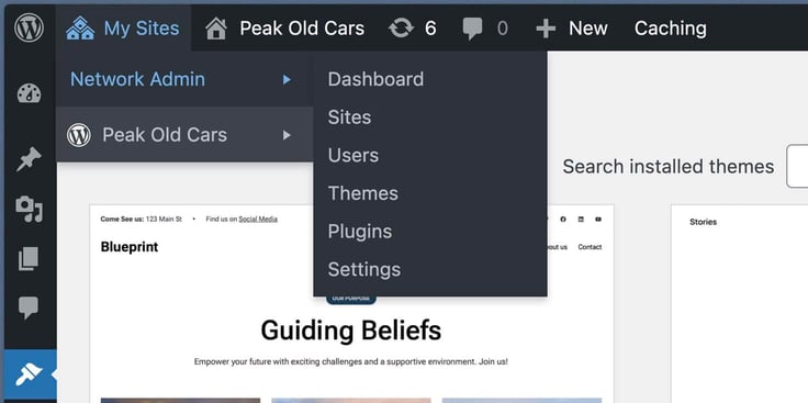 The WordPress admin toolbar dropdown menu displays "My Sites" expanded to show "Network Admin" and "Peak Old Cars" options, with Network Admin further expanded to reveal Dashboard, Sites, Users, Themes, Plugins, and Settings links, layered over a partially visible "Blueprint" themed website featuring a "Guiding Beliefs" heading and site navigation in the background. The WordPress admin toolbar dropdown menu displays "My Sites" expanded to show "Network Admin" and "Peak Old Cars" options, with Network Admin further expanded to reveal Dashboard, Sites, Users, Themes, Plugins, and Settings links, layered over a partially visible "Blueprint" themed website featuring a "Guiding Beliefs" heading and site navigation in the background.