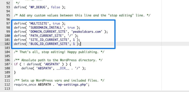 The wp-config.php file open in a code editor reveals the multisite network constants boxed in blue on lines 97 through 102, including MULTISITE set to true, SUBDOMAIN_INSTALL set to true, DOMAIN_CURRENT_SITE set to peakoldcars.com, plus PATH_CURRENT_SITE, SITE_ID_CURRENT_SITE, and BLOG_ID_CURRENT_SITE definitions placed above the "stop editing" comment line. The wp-config.php file open in a code editor reveals the multisite network constants boxed in blue on lines 97 through 102, including MULTISITE set to true, SUBDOMAIN_INSTALL set to true, DOMAIN_CURRENT_SITE set to peakoldcars.com, plus PATH_CURRENT_SITE, SITE_ID_CURRENT_SITE, and BLOG_ID_CURRENT_SITE definitions placed above the "stop editing" comment line.