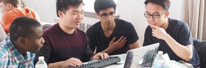 Photo of students gathered around a computer Photo of students gathered around a computer