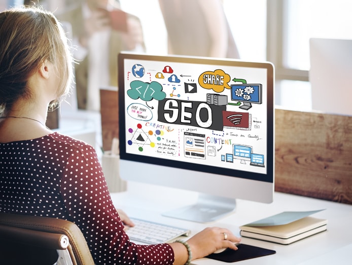 Photo of a woman at a computer with SEO concepts on the screen Photo of a woman at a computer with SEO concepts on the screen
