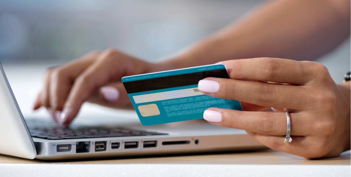 Image of someone holding a credit card to make a payment on a laptop